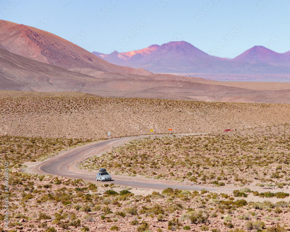 carro trafegando em rota rural no deserto do atacama durante pôr do sol 