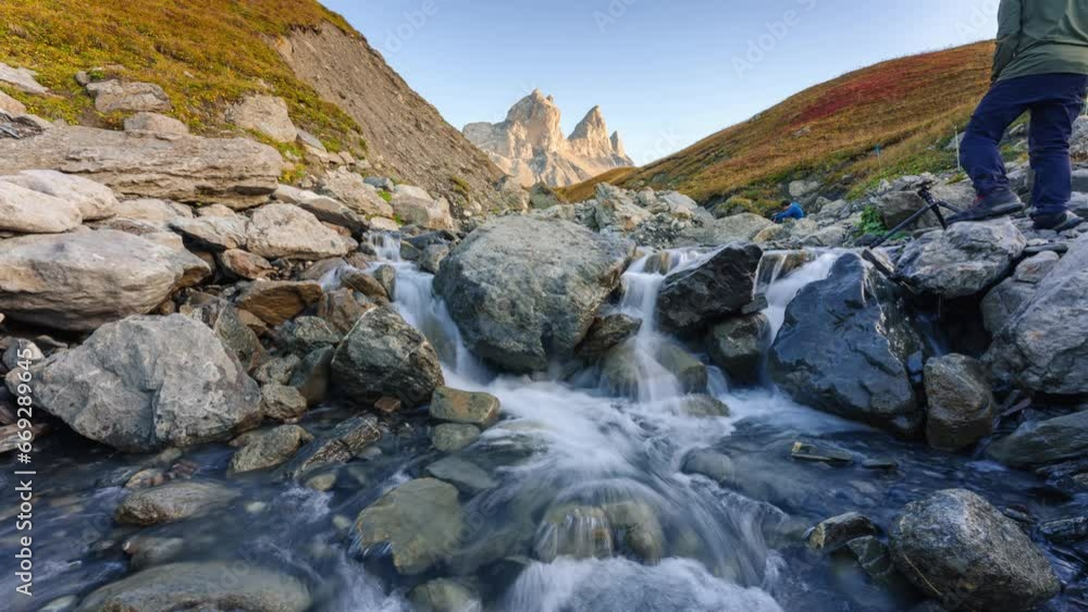 Landscape iconic three peak mountain with waterfall flowing and tourist taking pictures in valley of Aiguilles d Arves in French alps on autumn at Savoie, France Landscape iconic three peak mountain with waterfall flowing and tourist taking pictures in valley of Aiguilles d Arves in French alps on autumn at Savoie, France