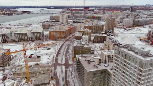 Helsinki.Finland-February 3.2022: Aerial shot of a new residential area next to West terminal called Jatkasaari. Ongoing construction. Cloudy sky. Drone moving backwards while tilting upwards. photo