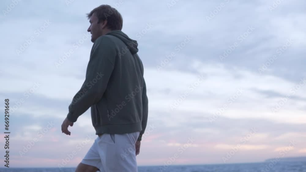 Handsome Russian man walking along the sea in the evening Handsome Russian man walking along the sea in the evening