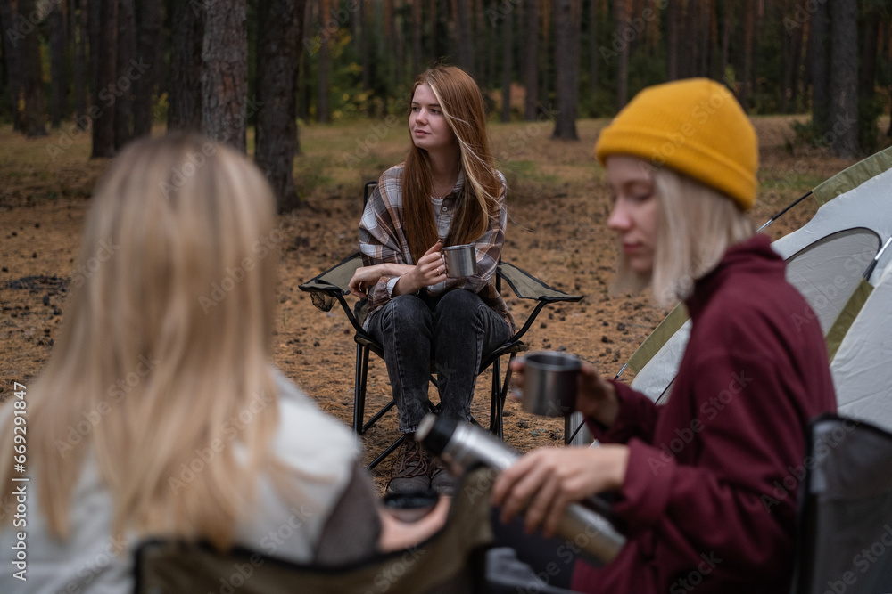 A group of girlfriends vacationing in the woods with tents in the fall. Happy women spend the weekend in nature.