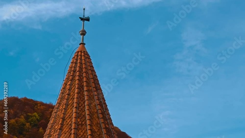 Tower with red tiling on the pointed roof. View of the top of Bran castle in Romania. Colorful nature at backdrop. photo