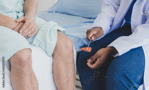 Closeup hand physical therapist woman doctor nurse African-American sitting holding cheack leg patient injury caucasian man two people talk helping support give advice inside treatment room hospital