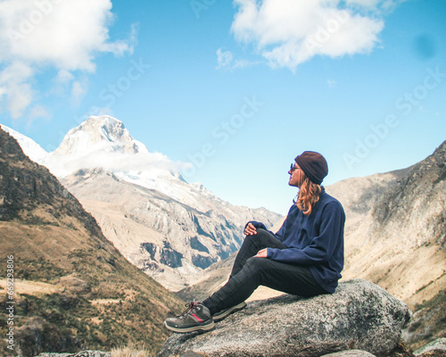mulher sentada em mirante com montanhas cobertas de neve ao fundo, no Parque Nacional Huscarán, no Peru photo