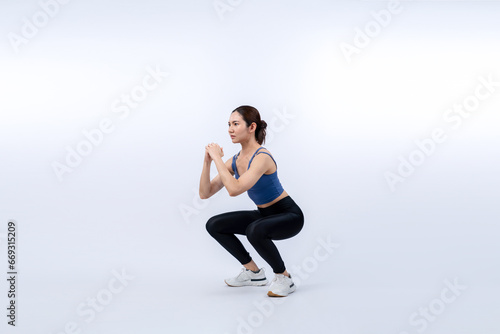 Vigorous energetic woman doing exercise. Young athletic asian woman strength and endurance training session as squat workout routine session. Full body studio shot on isolated background.