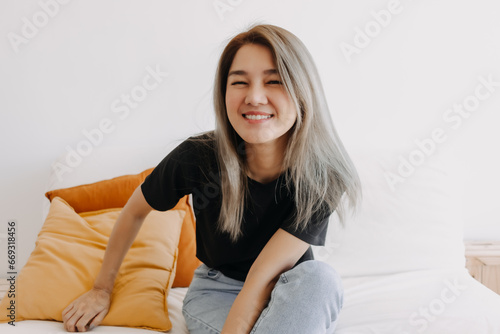 Happy asian woman sits and relax on sofa in one good fine day.