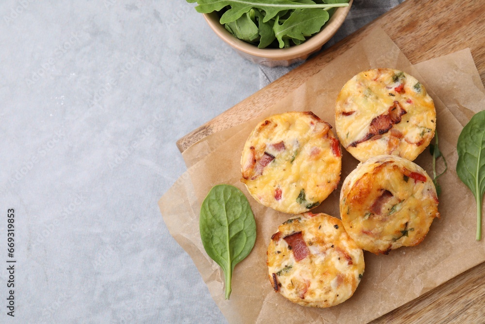 Delicious egg muffins with cheese and bacon on grey table, flat lay. Space for text Delicious egg muffins with cheese and bacon on grey table, flat lay. Space for text