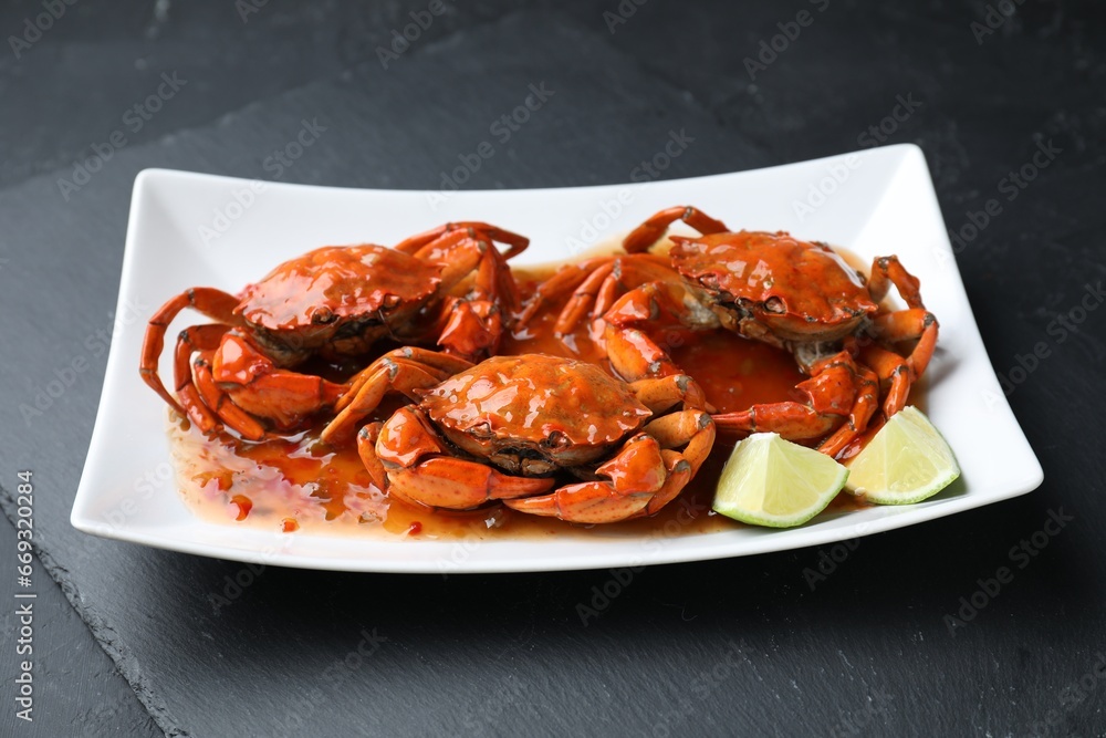 Delicious boiled crabs with sauce and lime on black textured table Delicious boiled crabs with sauce and lime on black textured table