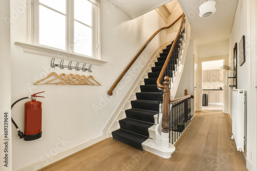 a staircase in a house with wood flooring and white trim on the stairs, there is a red fire exor