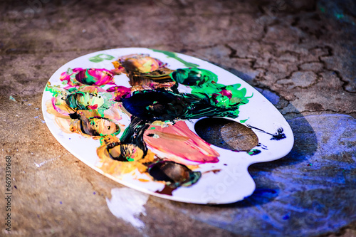 colorful paints spread on a white palette on top of a wooden desk