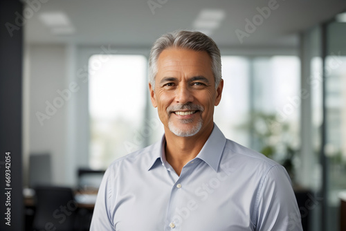 portrait of a senior businessman,Portrait of smiling senior businessman standing with arms crossed in modern office