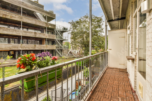 a balcony with flowers on the railings and an apartment building in the background, taken from inside to outside