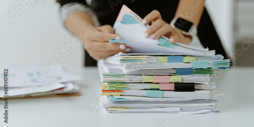 Businessman man working in stacks of papers searching for unfinished paperwork information on form check stack on table and checking financial papers in busy workload	 photo