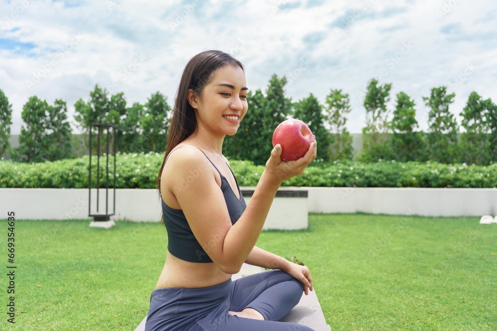 Fitness woman holding yoga mat with Fresh Apple Heathy clean vegan food before working out Beautiful confident asian woman practices in green park Fitness woman holding yoga mat with Fresh Apple Heathy clean vegan food before working out Beautiful confident asian woman practices in green park
