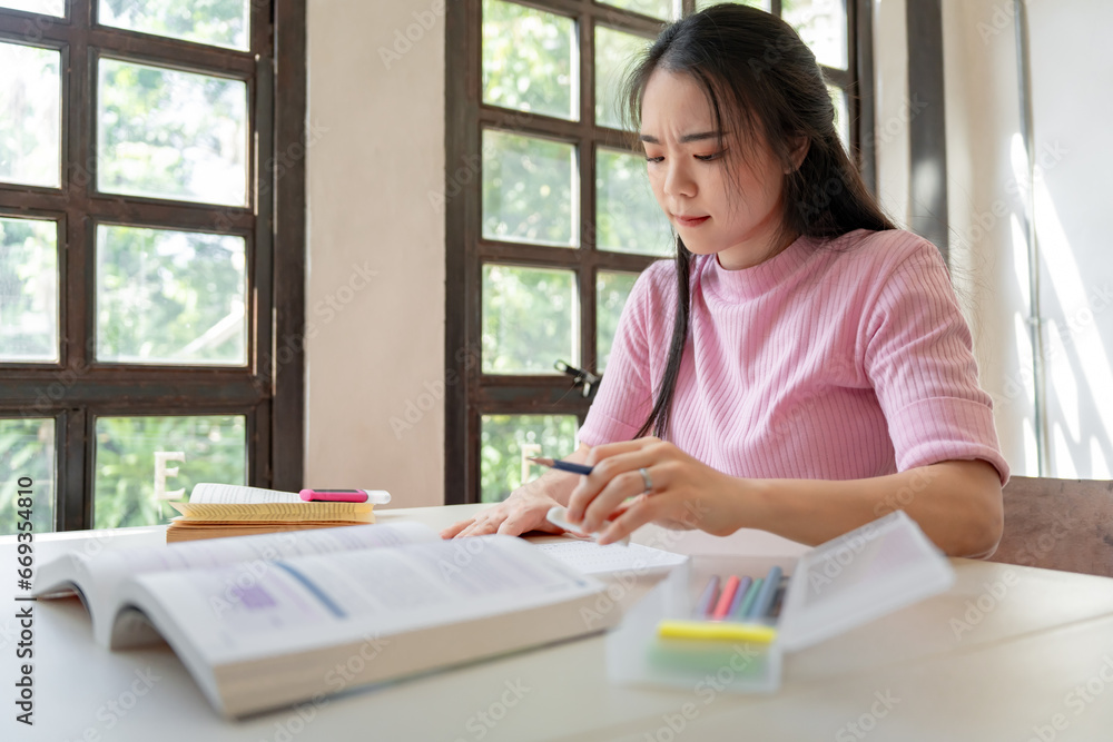 Asian girl student doing exam hand holding pencil writing answer in university classroom education high school or university student taking notes while preparing for exam Asian girl student doing exam hand holding pencil writing answer in university classroom education high school or university student taking notes while preparing for exam