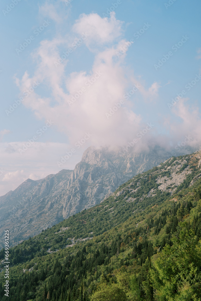 Fog over the peaks of a mountain range against a cloudy sky