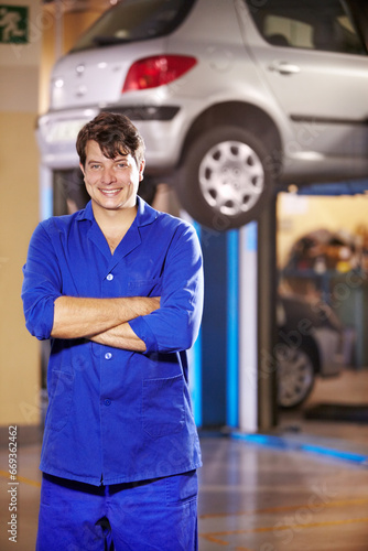 Portrait, happy man and mechanic with arms crossed at garage, service workshop or business. Confident, smile or professional technician, motor car repair expert or auto maintenance engineer in Canada