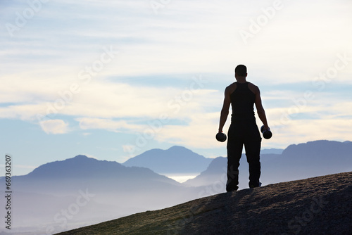 Fitness, weightlifting and back of man with dumbbells on mountain top for morning cardio on sky background. Weights, freedom and rear view of male bodybuilder in nature for training, power or workout © Thomas Talkner/peopleimages.com