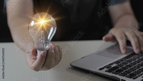 Idea innovation and inspiration concept. Hand of man holding illuminated light bulb, concept creativity with bulbs that shine glitter. Inspiration of ideas for sustainable business development.
