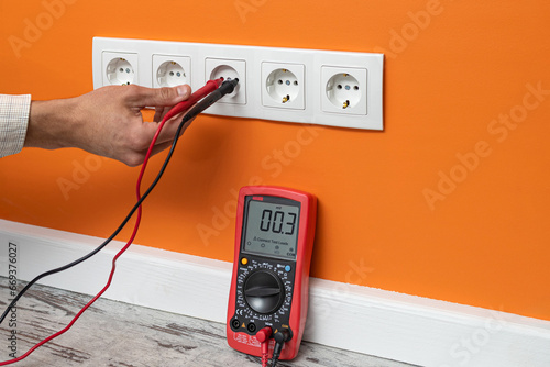 Man checking the voltage of electricity at a home outlet
