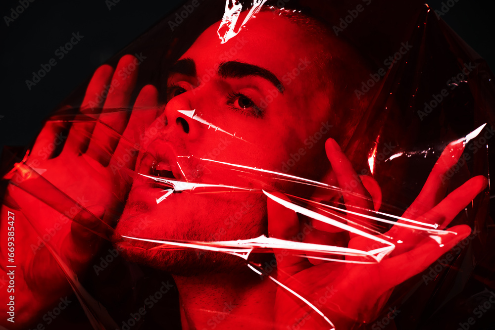 Man, red plastic and suffocating in studio isolated on black background ...