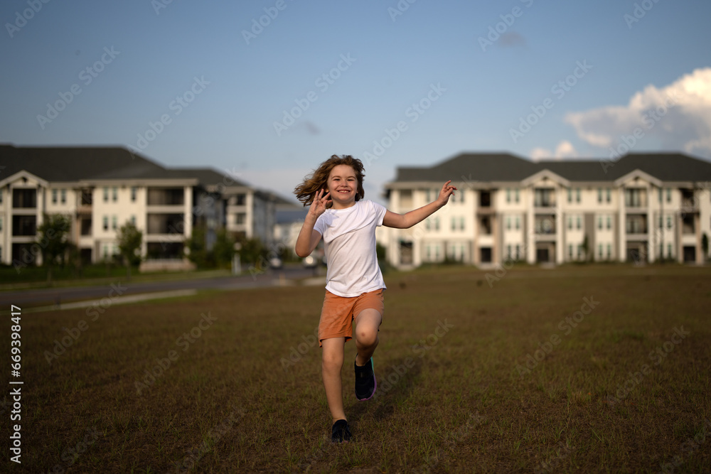 Child run. Excited kid boy running on grass. Kid boy playing and running in the summer park. Cute kid boy running across american neighborhood street. Summer, childhood, leisure and people concept.