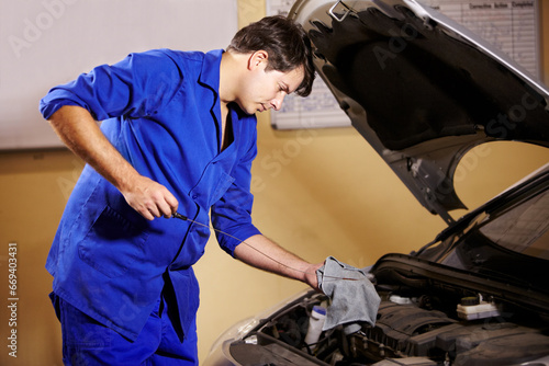 Mechanic, oil and service with a man in a workshop to fix or repair a vehicle during routine maintenance. Engineer, inspection and labor with a young person working in a garage for car assessment