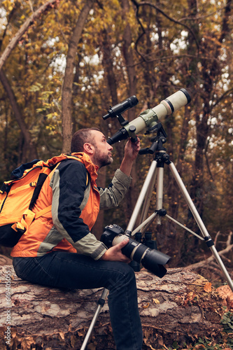 Man using telescope for bird and animal watching in nature. photo