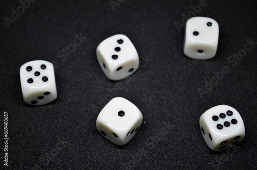 White dice are small  cube-shaped gaming accessories  on black background  They have blackpips on each face  are commonly used in various tabletop games.