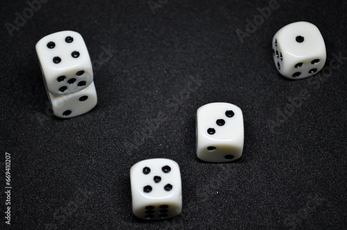 White dice are small  cube-shaped gaming accessories  on black background  They have blackpips on each face  are commonly used in various tabletop games.