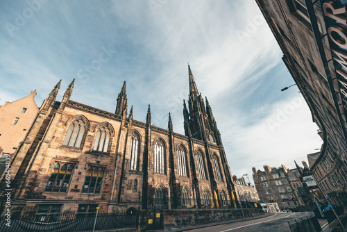 Edinburgh an imposing architecture with a towering structure alongside a bustling city street