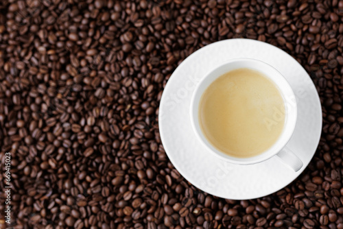 Top view of espresso with coffee foam in a cup on a dark background from coffee beans