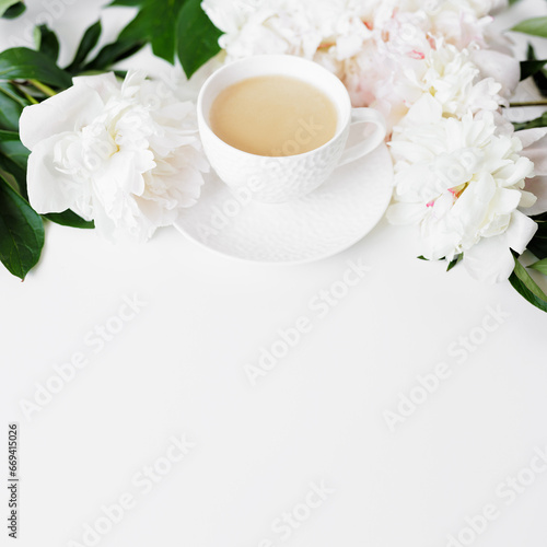 Morning coffee cup and white peonies flowers on white table