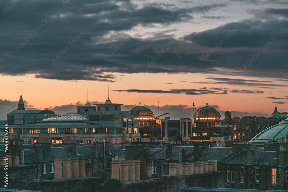 Edinburgh a vibrant cityscape illuminated by the setting sun with dramatic clouds overhead