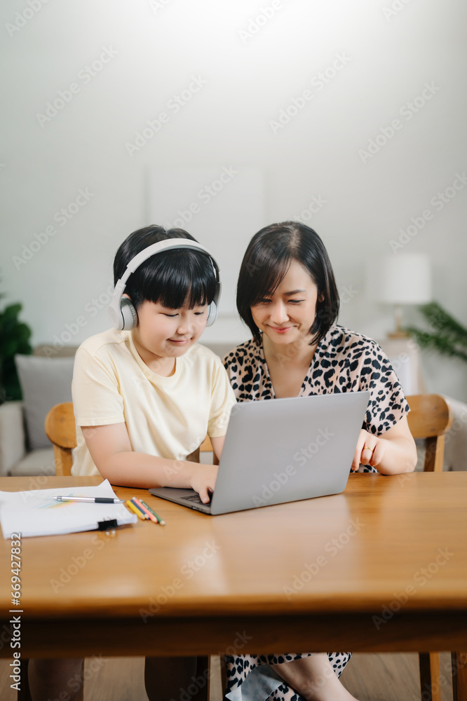 Homeschool Asian young little boy learning online and does homework by using computer and tablet with mother help, teach and encourage. son smile to study at home together with mom Homeschool Asian young little boy learning online and does homework by using computer and tablet with mother help, teach and encourage. son smile to study at home together with mom