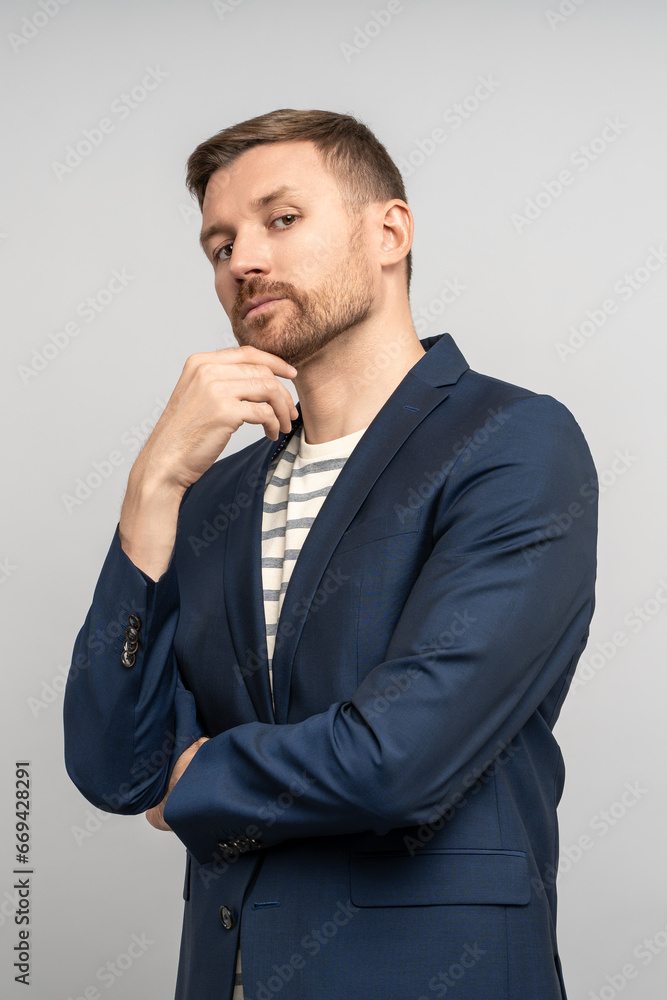 Serious stylish charismatic man looking like successful manager, businessman, entrepreneur, freelancer, employee, executive, marketer. Pensive unshaved man touching chin looking confidently at camera Serious stylish charismatic man looking like successful manager, businessman, entrepreneur, freelancer, employee, executive, marketer. Pensive unshaved man touching chin looking confidently at camera