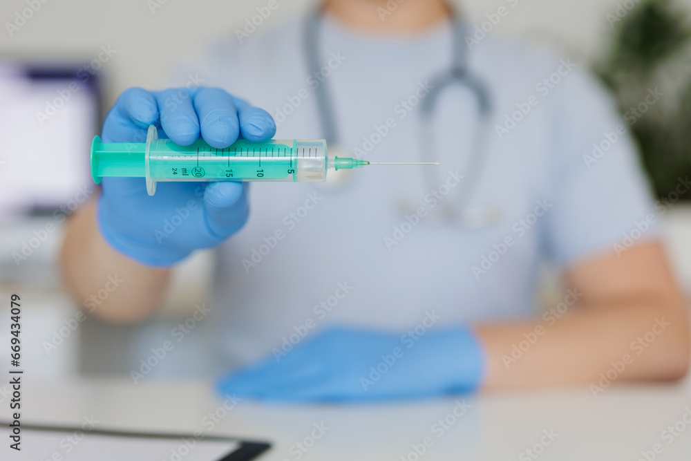 Close up of hand in glove holding syringe Close up of hand in glove holding syringe