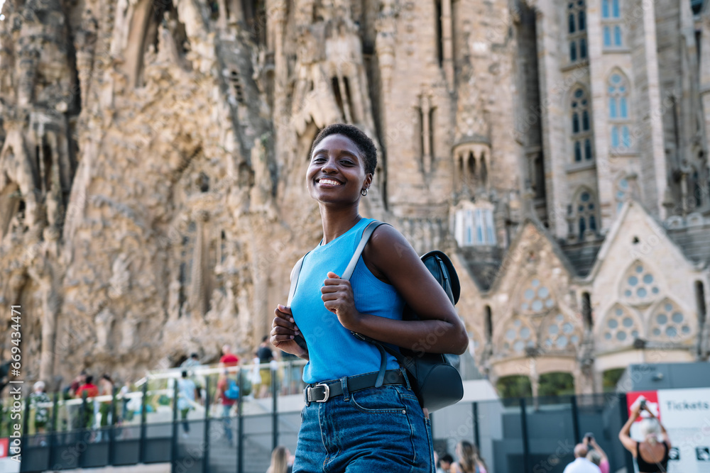Cheerful afro woman posing visiting a famous Church in Barcelona