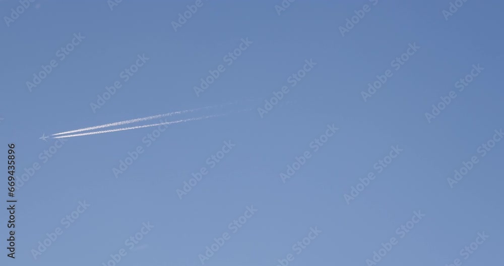 Airplane flying on deep blue sky with chemical direction trails, view from a distance Airplane flying on deep blue sky with chemical direction trails, view from a distance