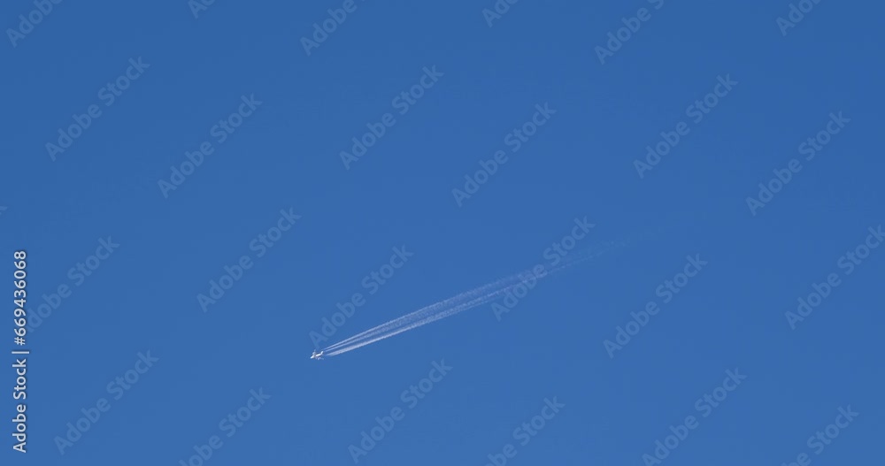 Airplane flying on deep blue sky with chemical direction trails, view from a distance Airplane flying on deep blue sky with chemical direction trails, view from a distance