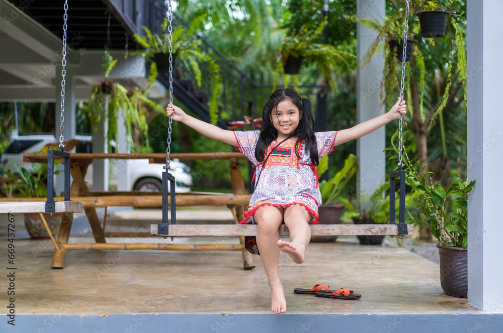 happy asian child or kid girl smiling sitting rest relax and playing on wooden swing with trees at home garden and family car on holiday and smile cheerful on green nature and wearing hilltribe outfit happy asian child or kid girl smiling sitting rest relax and playing on wooden swing with trees at home garden and family car on holiday and smile cheerful on green nature and wearing hilltribe outfit