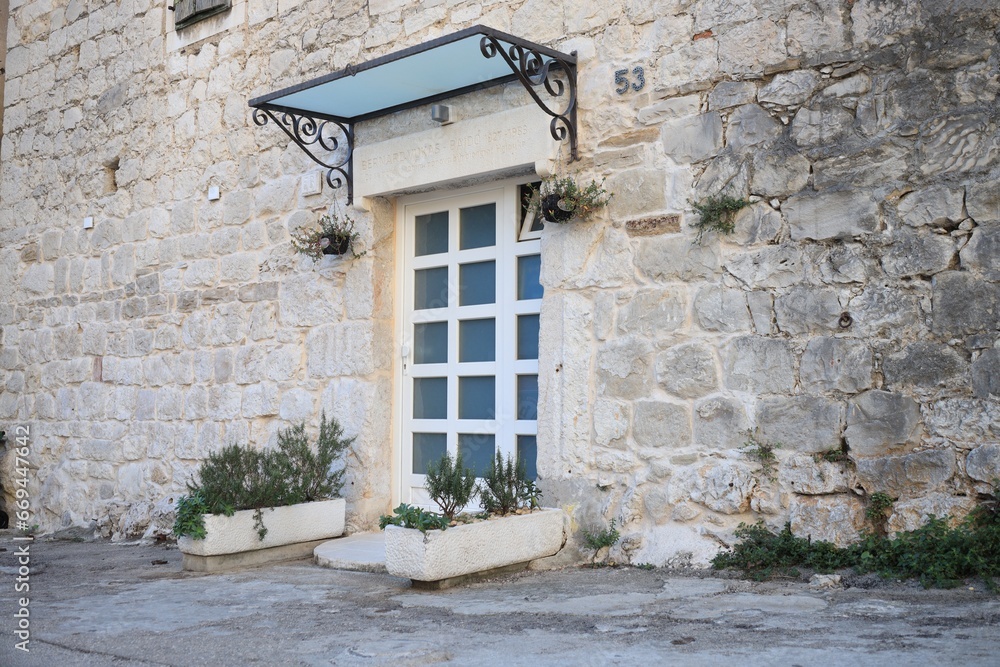 Entrance of residential house with white door in stone wall and potted plants
