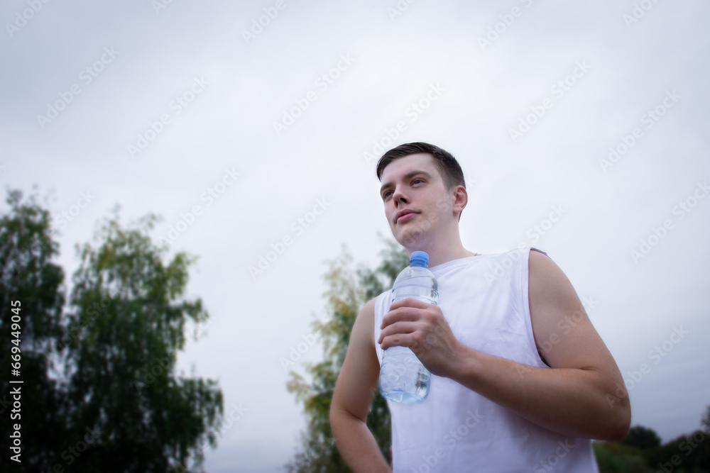 A man drinks water after jogging. Portrait Of Athletic Man in Sportswear A man drinks water after jogging. Portrait Of Athletic Man in Sportswear