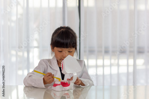 Little cute funny girl holding tooth jaw, toothbrush. Kid training oral hygiene. Child learning brushing, cleaning teeth. Prevention of caries in children. children dentistry. dental care kids