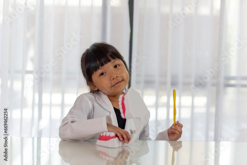 Little cute funny girl holding tooth jaw, toothbrush. Kid training oral hygiene. Child learning brushing, cleaning teeth. Prevention of caries in children. children dentistry. dental care kids