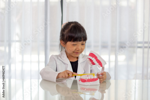 Little cute funny girl holding tooth jaw, toothbrush. Kid training oral hygiene. Child learning brushing, cleaning teeth. Prevention of caries in children. children dentistry. dental care kids