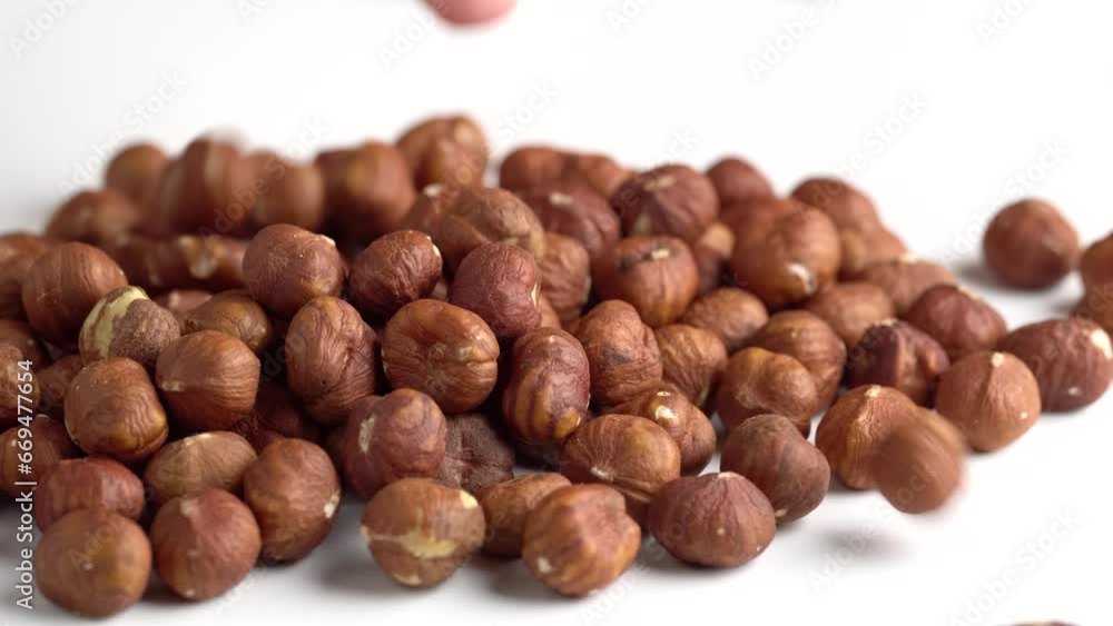 Hazelnuts falling on the white table. Woman holding hazelnuts in hand, closeup. Organic snack Hazelnuts falling on the white table. Woman holding hazelnuts in hand, closeup. Organic snack