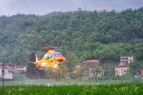 Helicopter emergency medical service taking off from a hospital helipad in heavy rain during a severe thunderstorm