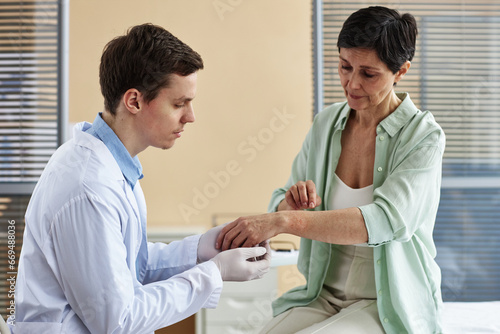 Canvas Print Side view portrait of doctor examining hands of mature woman during consultation