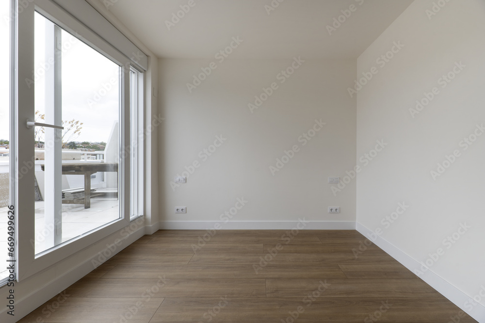 Panoramic view of a living room with wooden floors and access to a terrace in an apartment through a glass partition Panoramic view of a living room with wooden floors and access to a terrace in an apartment through a glass partition